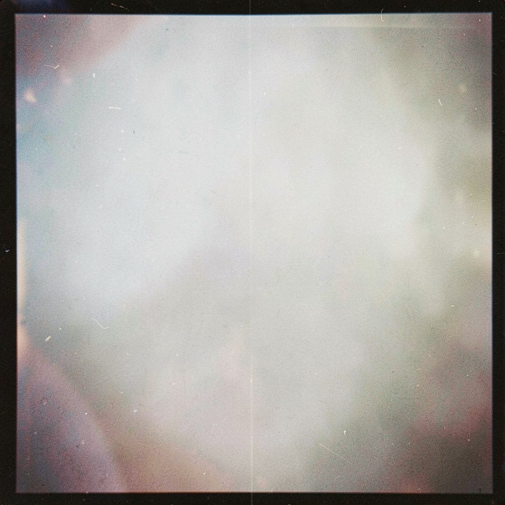 Grainy analog film photograph of a muddy outdoor obstacle course rope climb at dusk, muted olive green and brown tones, atmospheric fog, gritty determined mood